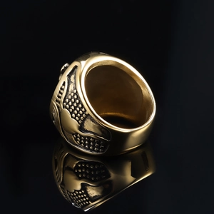 Close-up of a vintage golden lion head ring with embossed texture on black mirror