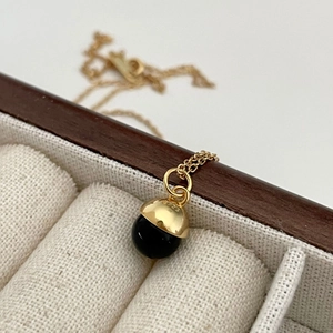 Macro detail of S925 sterling silver stamp on golden cap with black onyx bead pendant
