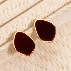 Detail of 18K gold-plated earrings with deep red flocking on beige textured fabric