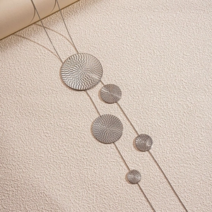 Detail shot of silver long tassel necklace with textured circular metal pendants and layers