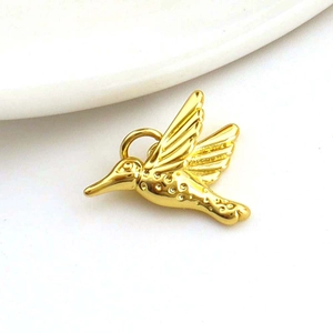 Detailed close-up of a 18k gold plated hummingbird pendant with intricate wing textures