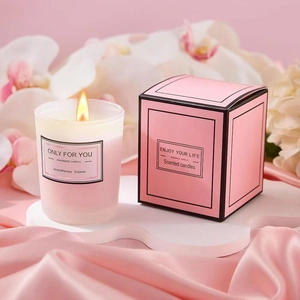 Close-up of pink scented soy candle in frosted glass with decorative gift box packaging