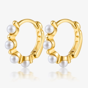 Detail view of gold geometric hoop earrings with integrated white shell pearls on white background