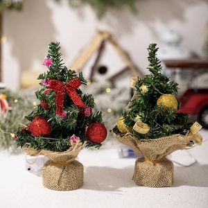 Detailed close-up of mini red and gold Christmas trees with LED lights and burlap base