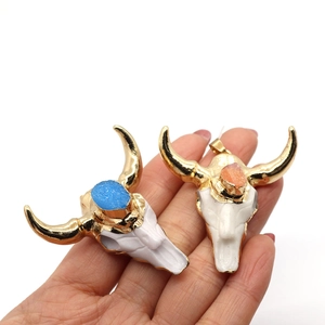 Detailed view of resin bull head pendants with gold horns and blue or pink crystals