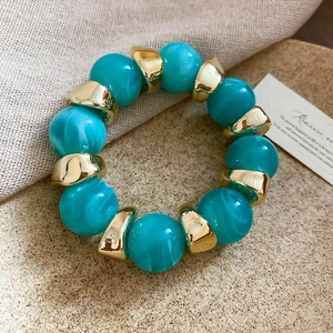 Detail of turquoise marble acrylic beads and golden metal spacers on elastic bracelet