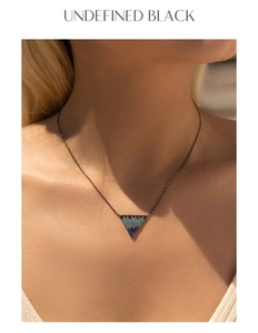 Macro detail of S925 silver inverted triangle pendant with gradient crystals on black chain