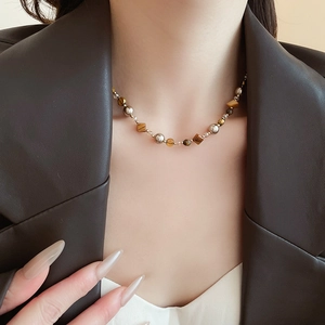 Nahaufnahme der Perlenkette mit Tigerauge und Perlen am Model im braunen Ledermantel