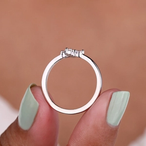 Close-up of minimalist silver ring with three micro-set diamonds and polished finish