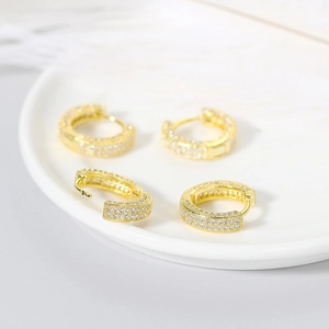 Close-up of gold-plated hoop earrings with micro-pave white zircon on a white plate