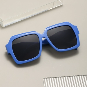 Modern unisex square sunglasses with thick blue frames and black lenses on grey surface