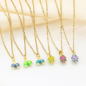 Detail of gold stainless steel necklaces with colorful enamel fruit charms like cherries