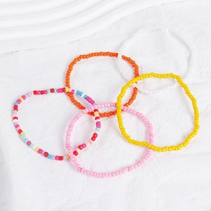 Detail of five-piece Bohemian stackable seed bead bracelet set on white textured fabric
