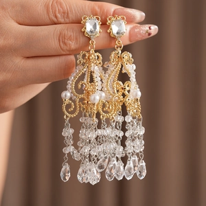 Detail of luxury chandelier earrings featuring gold tassels, crystals, and drop pearls