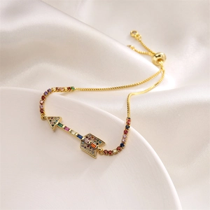 Detail of adjustable gold bracelet featuring a multi-color zircon arrow pendant on satin