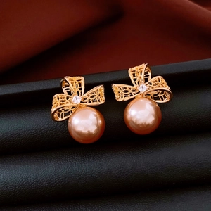 Vue macro détaillée de boucles d'oreilles nœud plaqué or 18k avec perle champagne