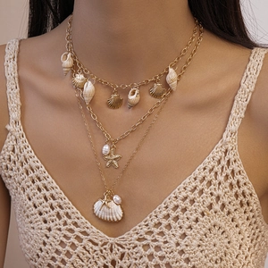 Détail d'un collier doré multi-rangs avec pendentifs coquillages et étoile de mer