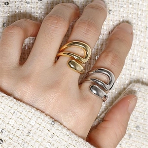 Close-up of minimalist gold and silver open rings with polished fluid design on model