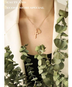 Détail du collier avec croix dorée et pendentif Madone sur mannequin avec des feuilles