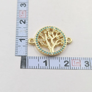 Macro view of gold Tree of Life pendant with turquoise crystals and ruler for size