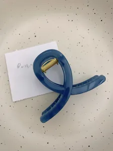 Détail de la pince à cheveux bleu Morandi avec ressort doré et design croisé élégant