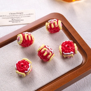 Detail of five red cake-shaped oil beads with heart patterns for DIY jewelry making