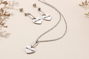 Macro shot of silver heart MOM engraved pendant and matching stud earrings set