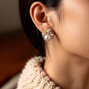 Detail of vintage flower pearl earrings with crystals worn by a model in knitwear