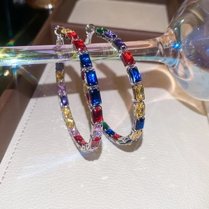 Macro shot of silver hoop earrings featuring rainbow cubic zirconia and sparkling light effects