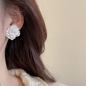 Close-up of a model wearing an elegant white floral pearl earring with refined textures