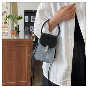 Detail of a mini denim and leather crossbody bag with silver hardware and top handle