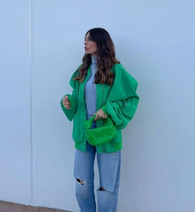 Street style view of bright green oversized jacket paired with ripped blue jeans