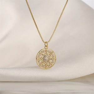 Dettaglio della collana totem sole d'oro con zirconi su seta color beige