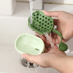 Dual-tone green silicone scalp massager brush being rinsed under running water
