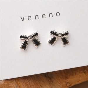 Detailed macro view of silver bow earrings with black enamel and m engraving