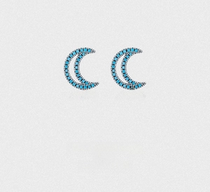 Macro detail of turquoise sterling silver crescent moon stud earrings on sand texture