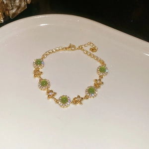 Detail view of gold-plated emerald flower bracelet with sparkling crystals and lobster clasp