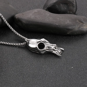 Detailed macro view of a silver animal skull pendant on textured dark stones