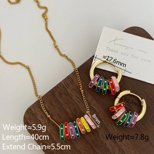 Macro shot of colorful enamel cylinder pendants on a gold necklace and hoop earrings