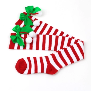 Detail of Christmas over-knee socks with red stripes, green bows and white pom-poms