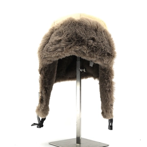 Detail view of winter beige trapper hat featuring thick faux fur lining and buckle strap