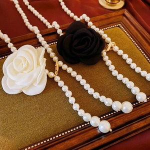 Détails des colliers à fleurs en tissu et perles sur fond de soie luxueuse