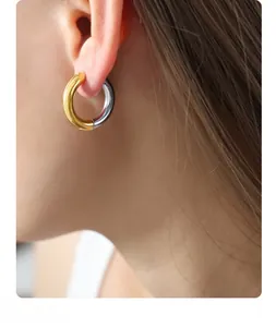 Close-up of a woman wearing chunky two-tone gold and silver plated stainless steel hoop earrings