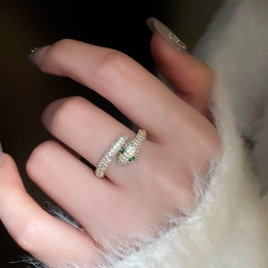 Detail of snake ring in gold plating with sparkling zircons and green gemstone eyes