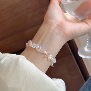 Close-up of butterfly and pearl beads on pink cord worn by a model in soft light