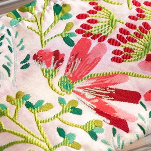 Close-up of premium jacquard fabric with red floral embroidery on pink pouch