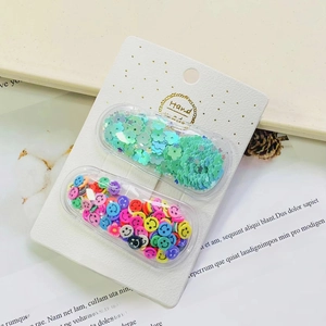 Macro detail of capsule hair clips filled with mint flower and smiley face sequins