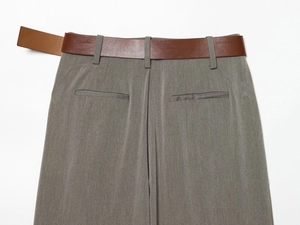 Vue détaillée d'un pantalon gris avec ceinture en cuir marron et poches arrière à passepoil