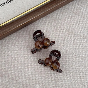 Detailed view of two dark brown amber-colored cherry hair claws on a textured surface