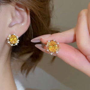 Close-up of 18k gold-plated oval yellow zircon earrings with white crystal accents
